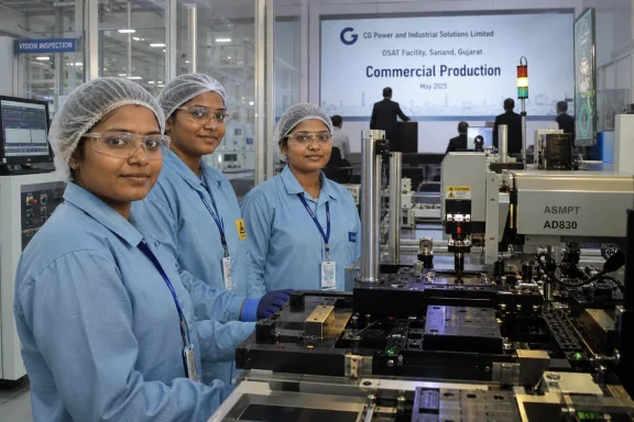 Three engineers in lab coats stand by an industrial production machine in a cleanroom with a “Commercial Production” sign.