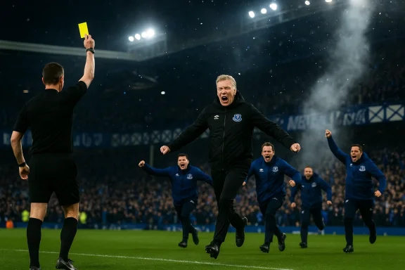 Referee raises a yellow card as blue-clad players celebrate on the pitch.